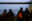 Vier Gerettete an Bord der Humanity 1 von hinten, wie sie auf das Meer und andere Schiffe blicken.