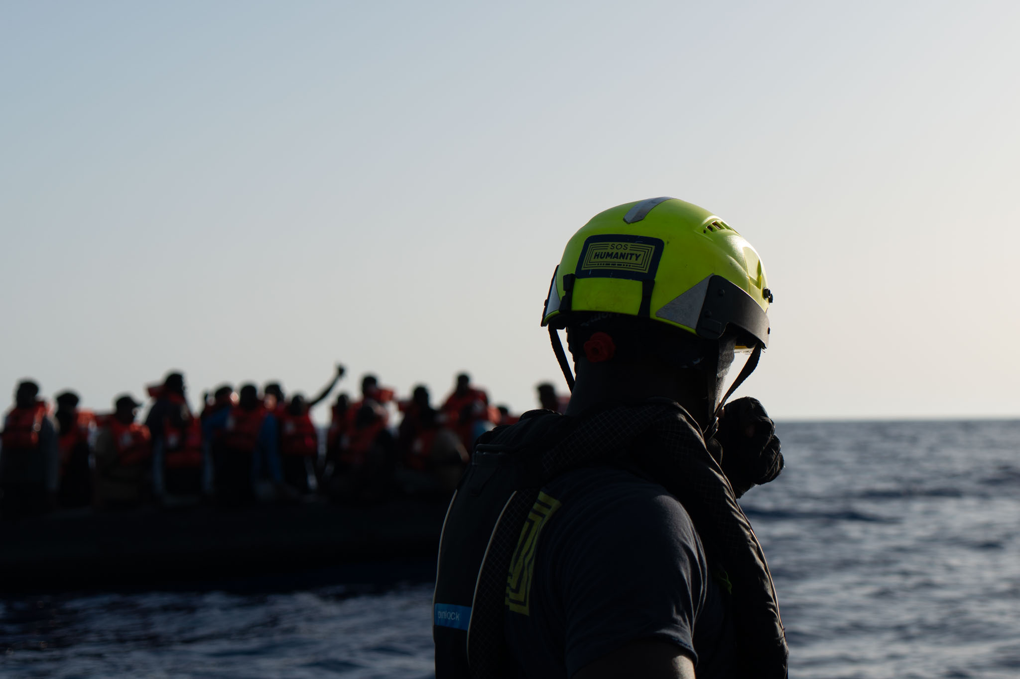 Ein Crewmitglied von SOS Humanity blickt während einer Rettungssituation auf ein Boot in Seenot, welches gerade Rettungswesten erhalten hat.