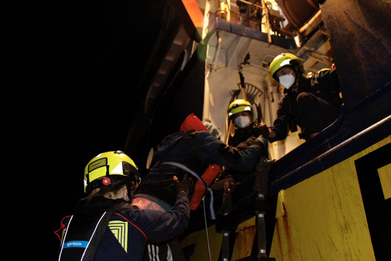 Einer geretteten Person wird vom schnellen Rettungsboot an Bord der Humanity 1 geholfen.