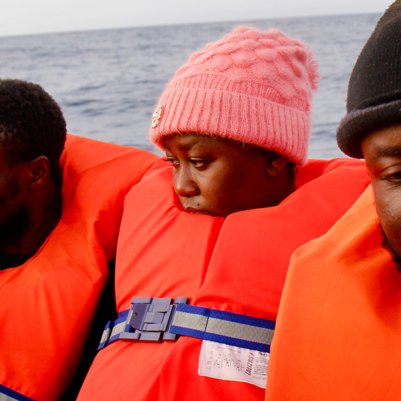 Eine Frau in Rettungsweste. Nur das Gesicht ist noch zu sehen und sie trägt eine rosafarbene Wollmütze.