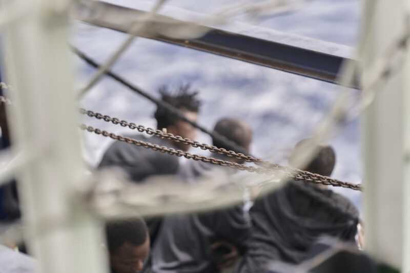 Überlebende an Bord der Humanity 1 hinter einem abgegrenzten Bereich, Meer im Hintergrund