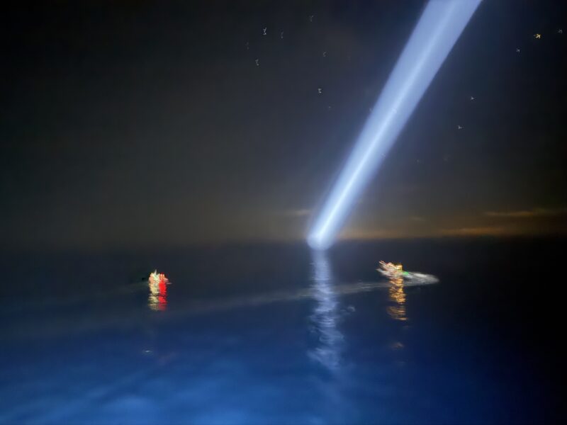 Lichtkegel von den Scheinwerfern der Humanity 1 über einem Flüchtlingsboot auf dem Mittelmeer