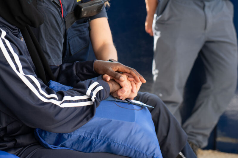 Zwei Hände greifen ineinander - es sind die Hände eines Geretteten und eines Crewmitglieds an Bord der Humanity 1