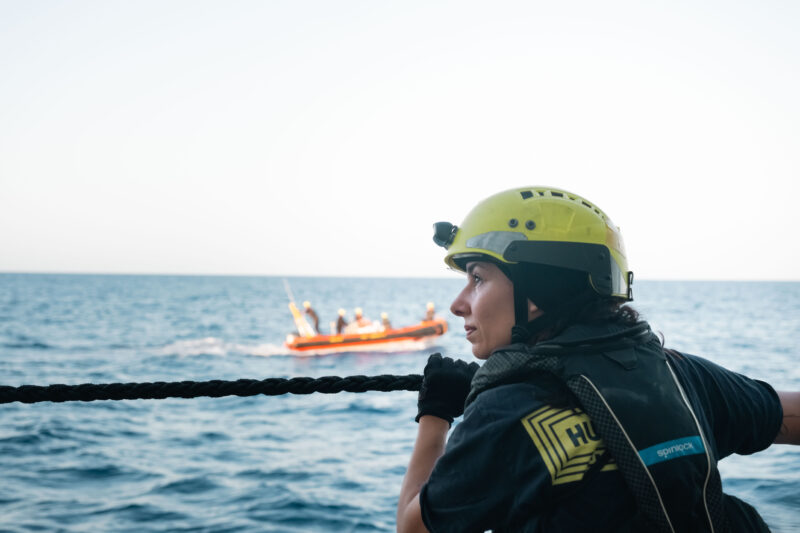 Crewmitglied von SOS Humanity blickt über die Reling des Rettungschiffs Humanity 1 auf das Mittelmeer.