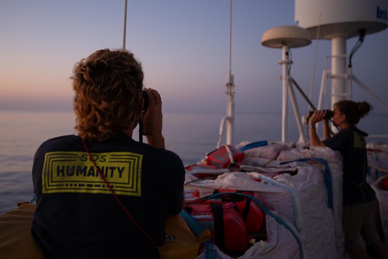 Zwei Crew-Mitglieder der Humanity 1 halten Ausschau nach Booten auf dem Zentralen Mittelmeer.