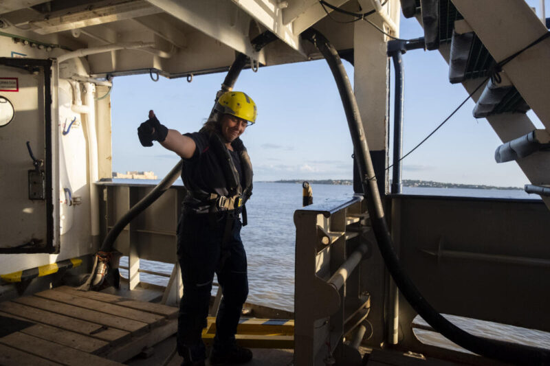 Frau mit Helm auf einem Rettungsschiff zeigt "Daumen hoch"