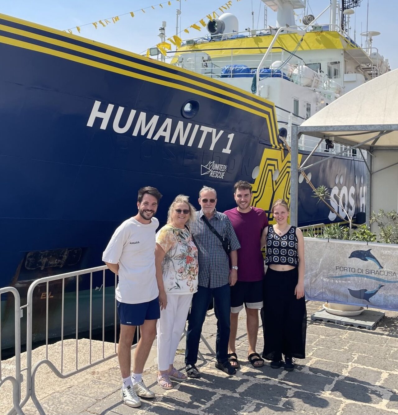 Personen stehen am Hafen vor dem Rettungsschiff Humanity 1