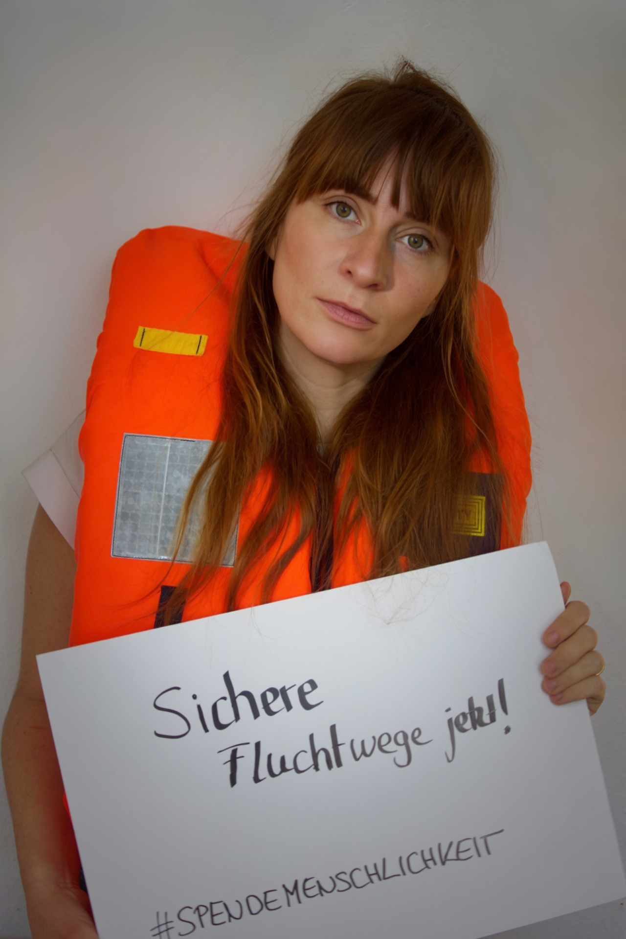 Foto von Thekla Wilkening, mit Schild in der Hand auf dem steht "Sichere Fluchtwege jetzt".
