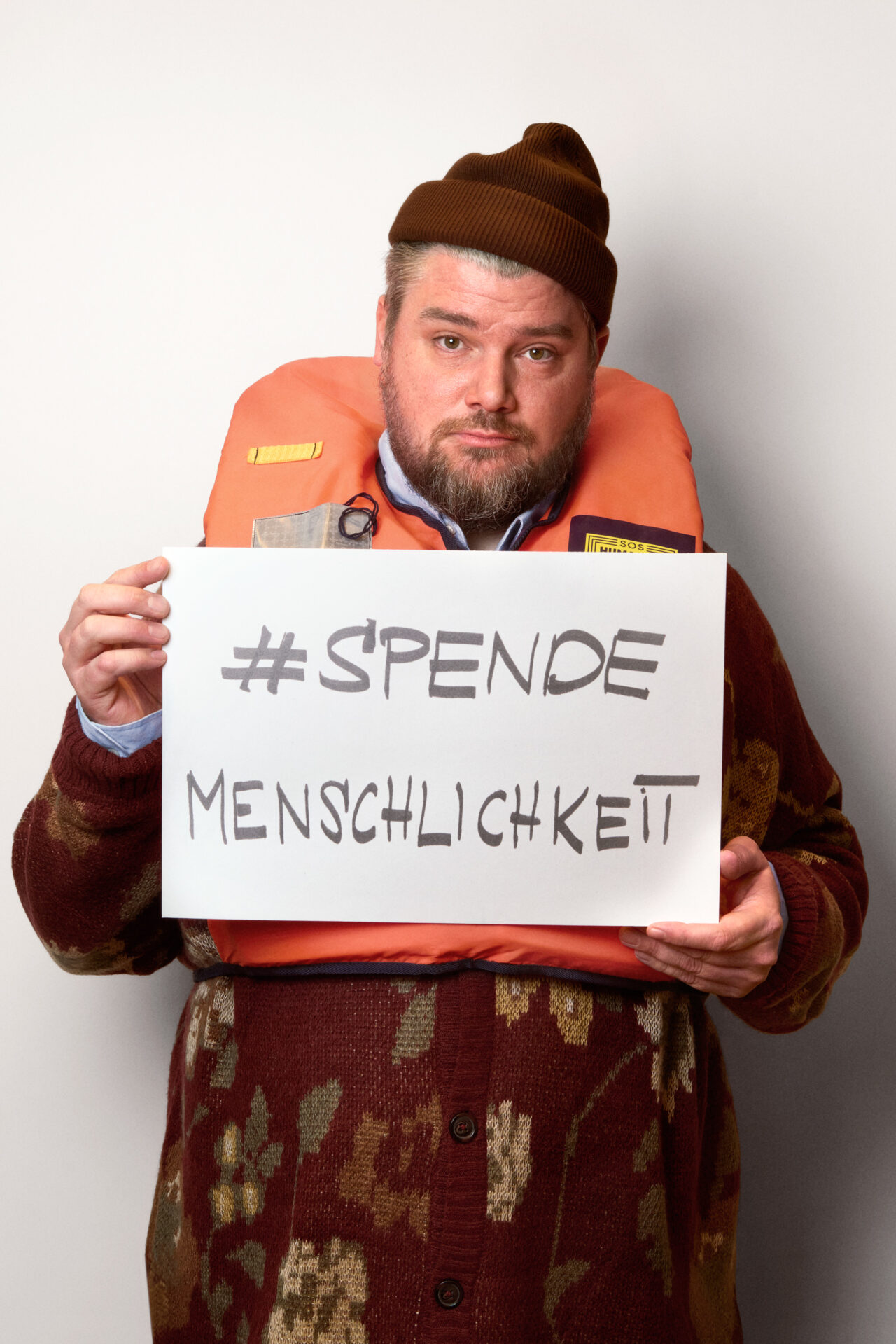 Foto von Bobbie Serrano mit Schild in der Hand auf dem steht "Spende Menschlichkeit"